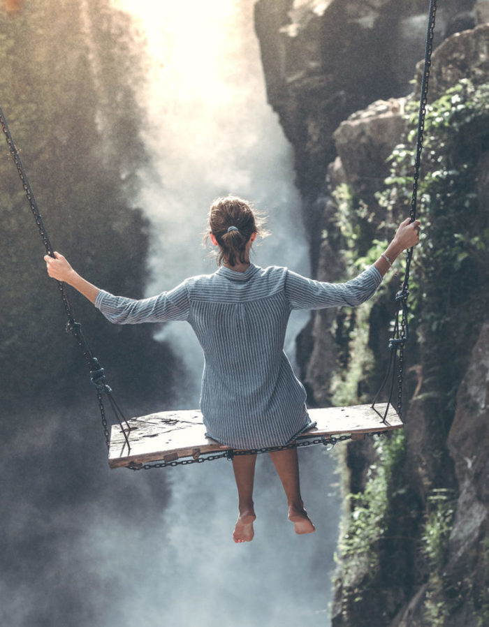 Femme sur une balançoire devant une chute d'eau