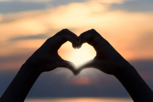 Technique énergétique Lahochi coeur avec les mains au coucher de soleil